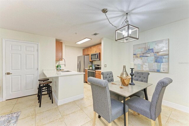 dining space featuring sink, light tile patterned flooring, and a notable chandelier