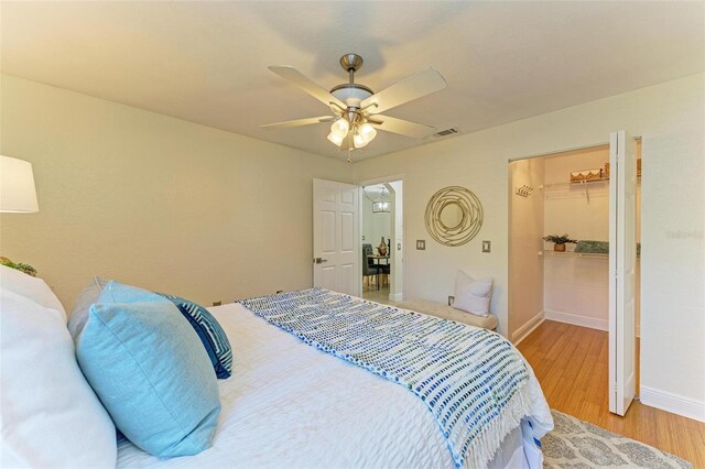 bedroom with a closet, a spacious closet, ceiling fan, and light hardwood / wood-style floors