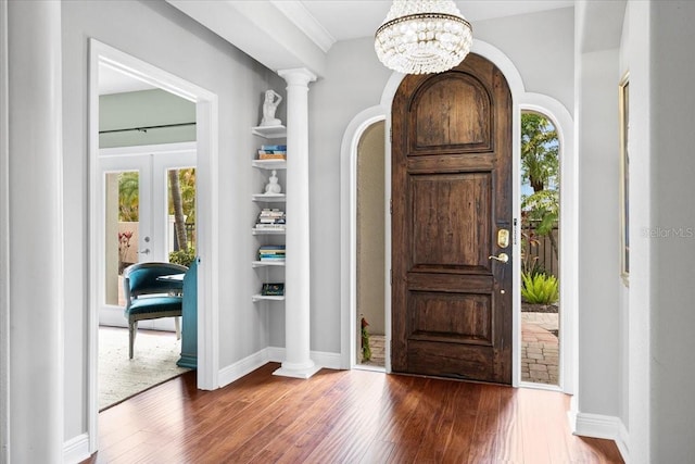 foyer entrance with plenty of natural light, dark hardwood / wood-style flooring, and decorative columns