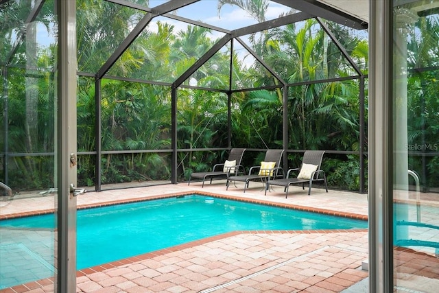 view of pool with a patio area and glass enclosure