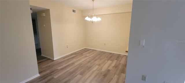 unfurnished room with wood-type flooring and an inviting chandelier