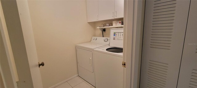 clothes washing area with washing machine and clothes dryer, light tile patterned flooring, and cabinets