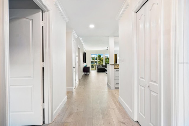 hall with ornamental molding and light hardwood / wood-style flooring