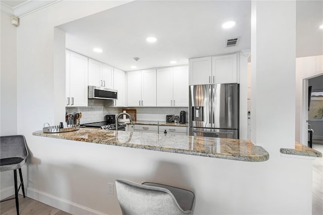 kitchen with kitchen peninsula, stainless steel appliances, and white cabinetry