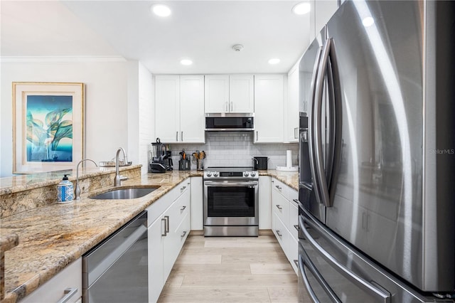 kitchen featuring white cabinetry, stainless steel appliances, decorative backsplash, light stone countertops, and sink