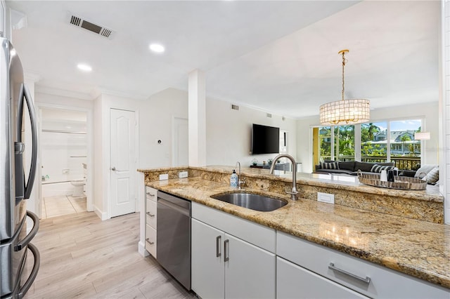 kitchen featuring white cabinets, stainless steel appliances, sink, hanging light fixtures, and light stone counters