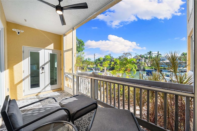 balcony featuring ceiling fan, french doors, and a water view