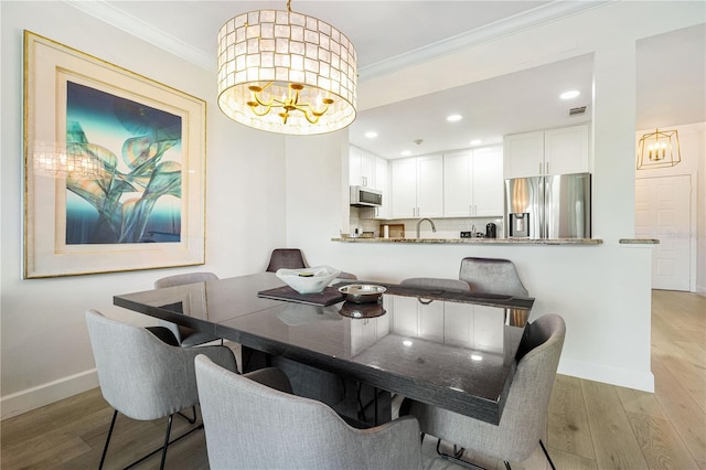 dining room featuring ornamental molding, light hardwood / wood-style flooring, and a notable chandelier