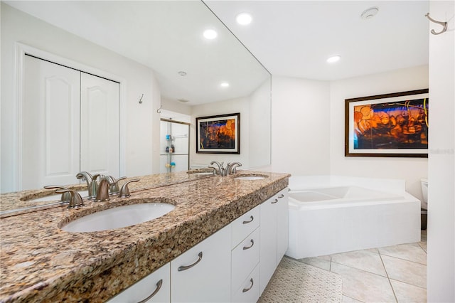 bathroom with toilet, vanity, tile patterned floors, and a relaxing tiled tub