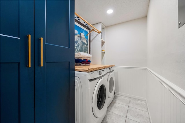 laundry room with washer and dryer, a textured ceiling, and light tile patterned flooring