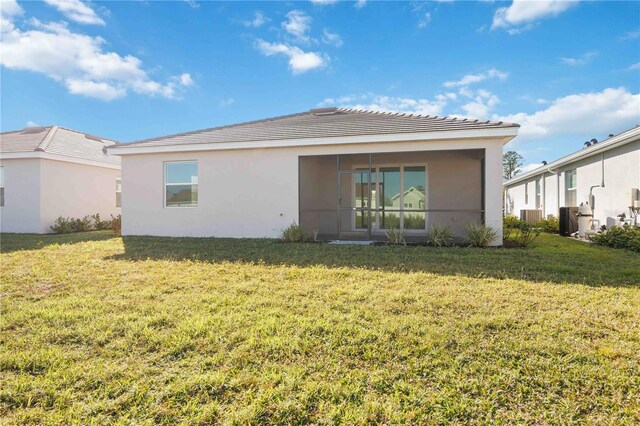 back of property featuring a yard and central AC