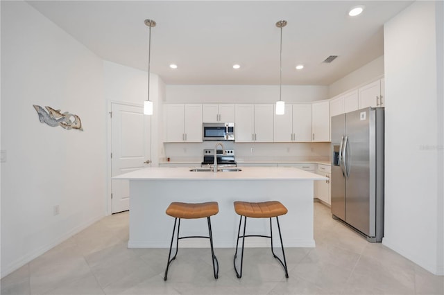 kitchen with white cabinetry, an island with sink, decorative light fixtures, and appliances with stainless steel finishes