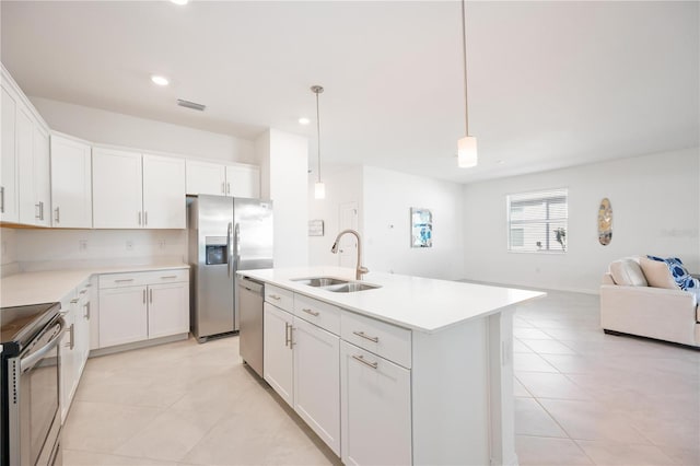 kitchen with stainless steel appliances, a kitchen island with sink, sink, pendant lighting, and white cabinets