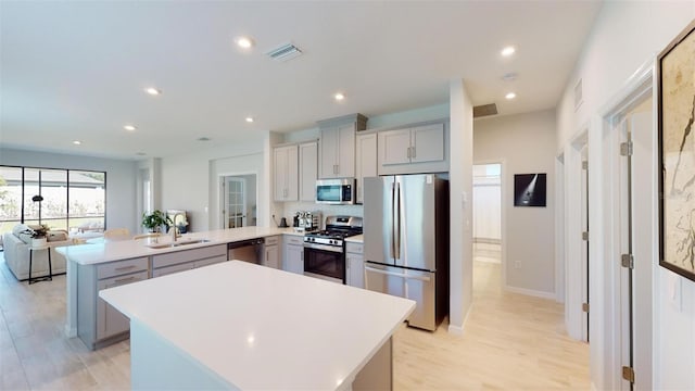 kitchen featuring sink, gray cabinets, light hardwood / wood-style floors, kitchen peninsula, and stainless steel appliances