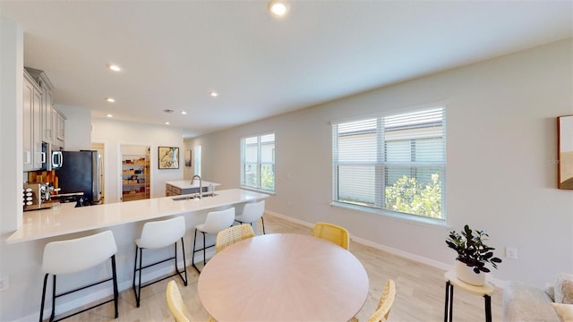 kitchen with kitchen peninsula, light wood-type flooring, a breakfast bar, stainless steel appliances, and sink