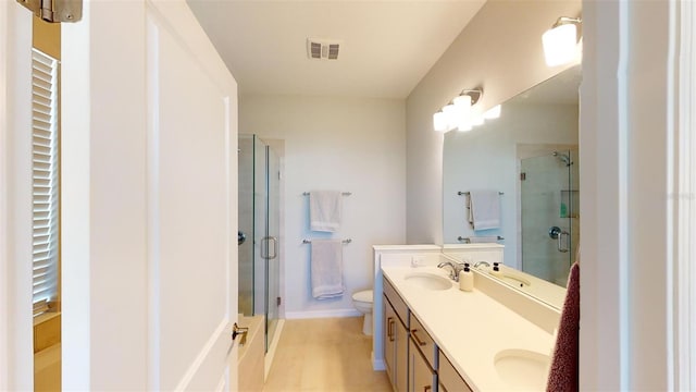 bathroom featuring tile patterned floors, vanity, toilet, and a shower with door