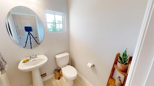 bathroom featuring wood-type flooring, toilet, and sink