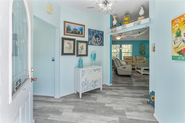 hallway with a notable chandelier and light hardwood / wood-style floors