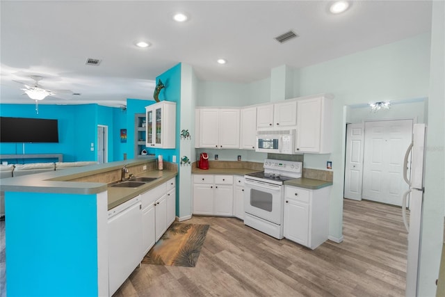 kitchen with kitchen peninsula, white appliances, sink, light hardwood / wood-style flooring, and white cabinets