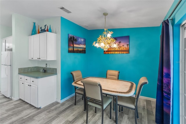 dining area featuring light wood-type flooring, an inviting chandelier, and vaulted ceiling