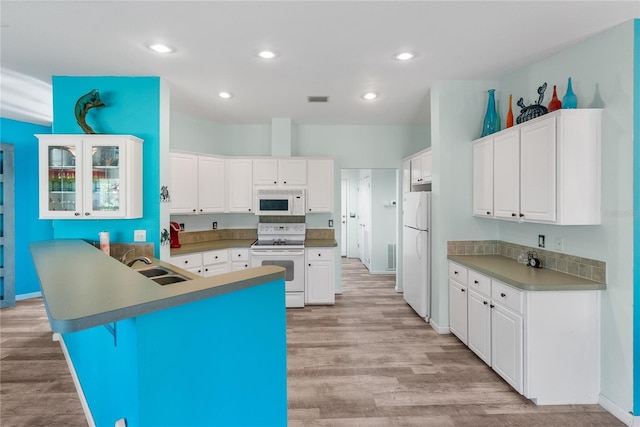 kitchen with a kitchen bar, light wood-type flooring, white appliances, sink, and white cabinetry