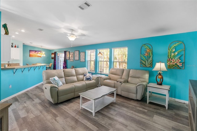 living room featuring ceiling fan with notable chandelier and hardwood / wood-style flooring