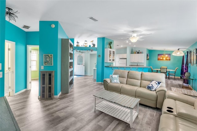 living room featuring ceiling fan with notable chandelier and hardwood / wood-style flooring