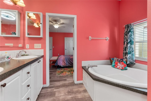 bathroom with ceiling fan, wood-type flooring, a bath, and vanity