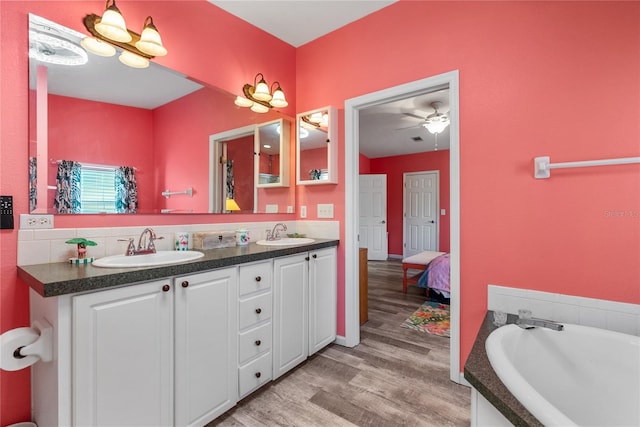 bathroom with vanity, hardwood / wood-style flooring, ceiling fan, and a tub