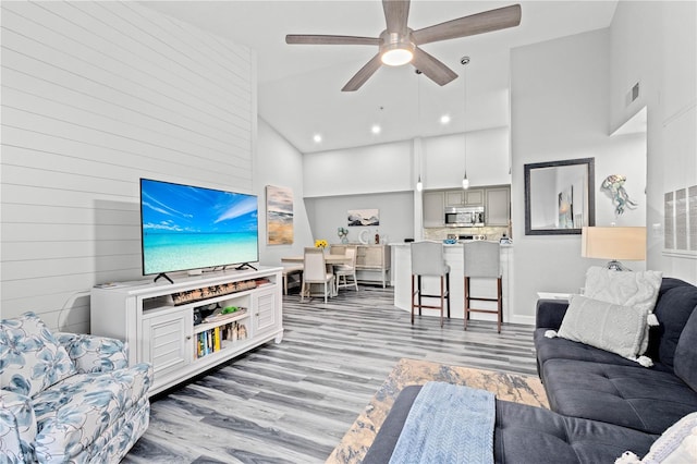 living room featuring light hardwood / wood-style floors, high vaulted ceiling, and ceiling fan