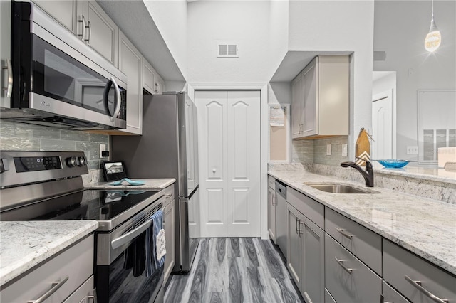 kitchen featuring backsplash, light hardwood / wood-style floors, stainless steel appliances, sink, and gray cabinets