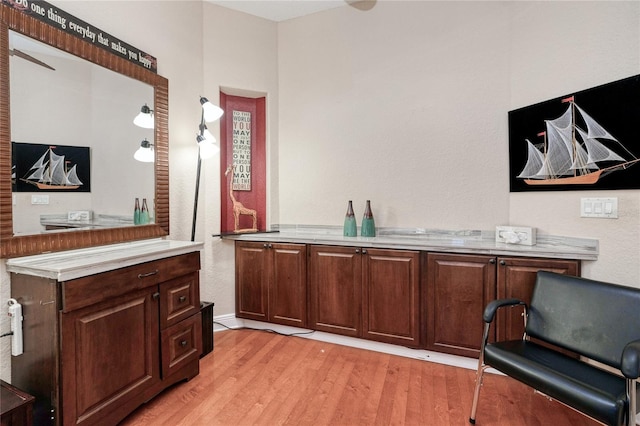 bar with light hardwood / wood-style floors and dark brown cabinetry