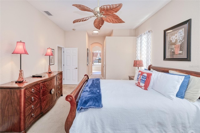 bedroom featuring light colored carpet, ceiling fan, and ensuite bathroom