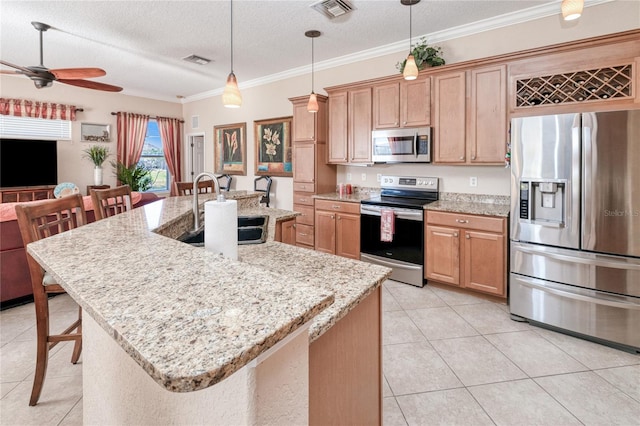 kitchen with a textured ceiling, stainless steel appliances, a kitchen island with sink, sink, and a breakfast bar area