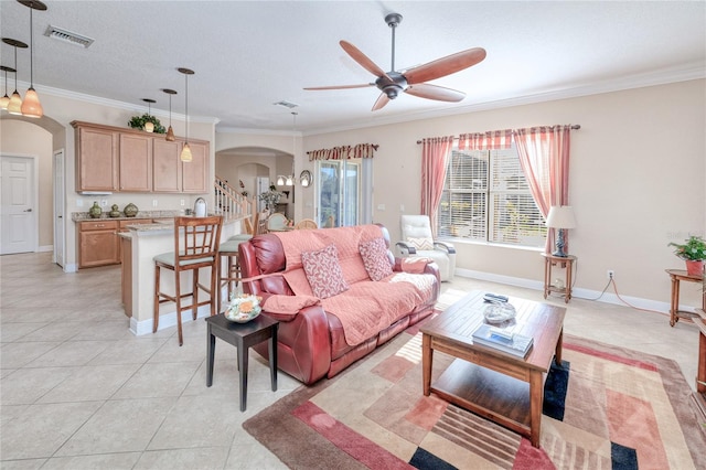 living room featuring ceiling fan, light tile patterned floors, a textured ceiling, and ornamental molding