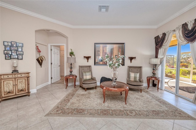 sitting room with baseboards, visible vents, arched walkways, and crown molding