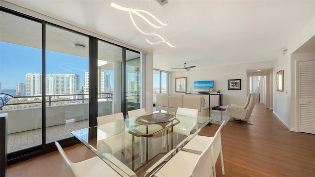 dining space with hardwood / wood-style floors, ceiling fan with notable chandelier, and a healthy amount of sunlight