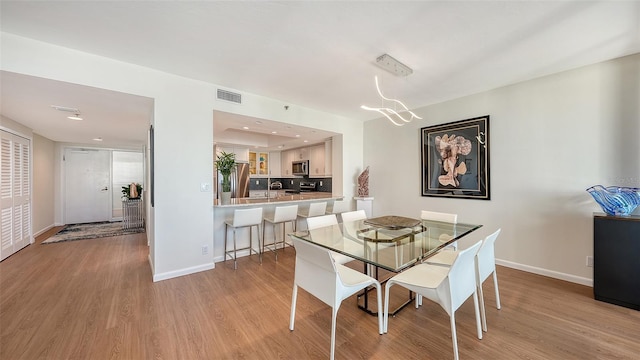 dining space with light hardwood / wood-style floors and an inviting chandelier