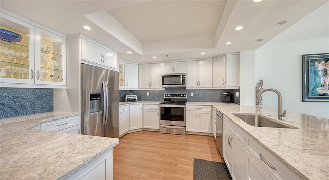 kitchen with white cabinets, sink, decorative backsplash, light hardwood / wood-style floors, and stainless steel appliances