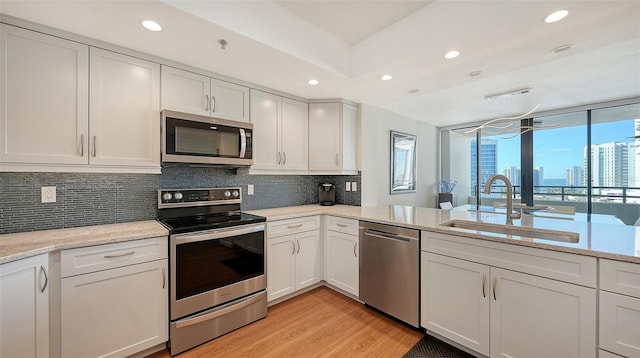 kitchen featuring sink, white cabinets, stainless steel appliances, and light wood-type flooring