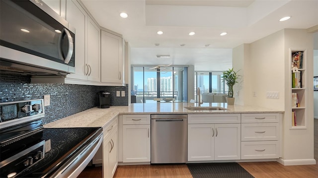 kitchen featuring white cabinets, stainless steel appliances, kitchen peninsula, and sink