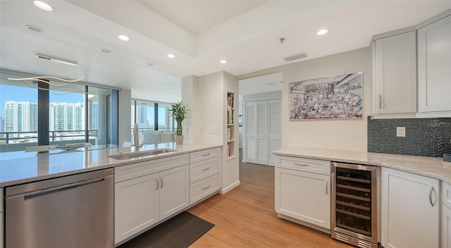 kitchen with wine cooler, light stone counters, stainless steel dishwasher, white cabinets, and light wood-type flooring