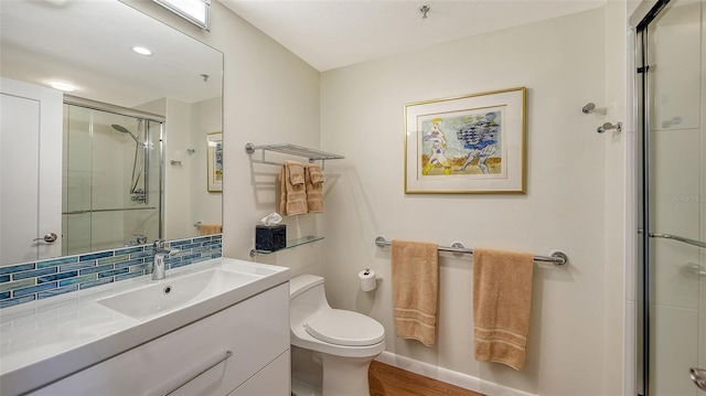 bathroom with tasteful backsplash, walk in shower, vanity, wood-type flooring, and toilet