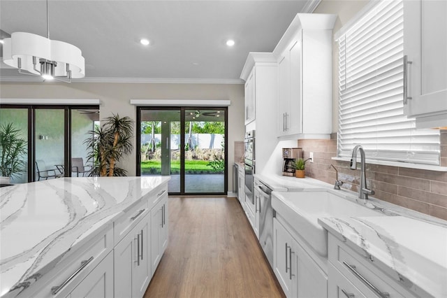 kitchen with pendant lighting, french doors, crown molding, light stone countertops, and white cabinetry