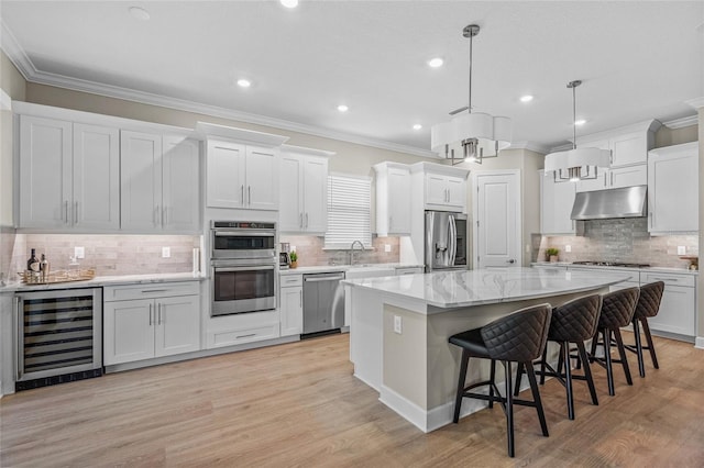 kitchen with white cabinets, a center island, stainless steel appliances, and wine cooler