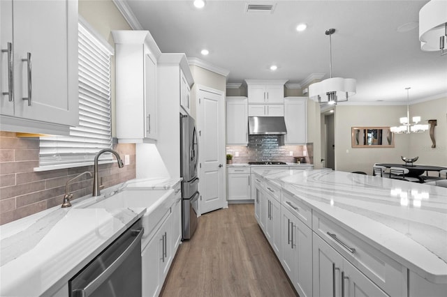 kitchen featuring backsplash, stainless steel appliances, light hardwood / wood-style flooring, white cabinets, and hanging light fixtures