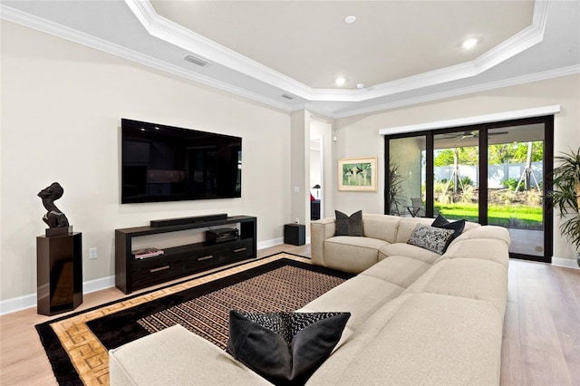 living room with a raised ceiling, crown molding, and light wood-type flooring