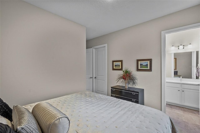 carpeted bedroom featuring a textured ceiling and ensuite bath