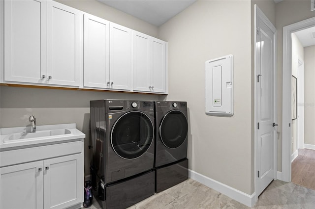 washroom featuring washer and clothes dryer, sink, cabinets, and light wood-type flooring