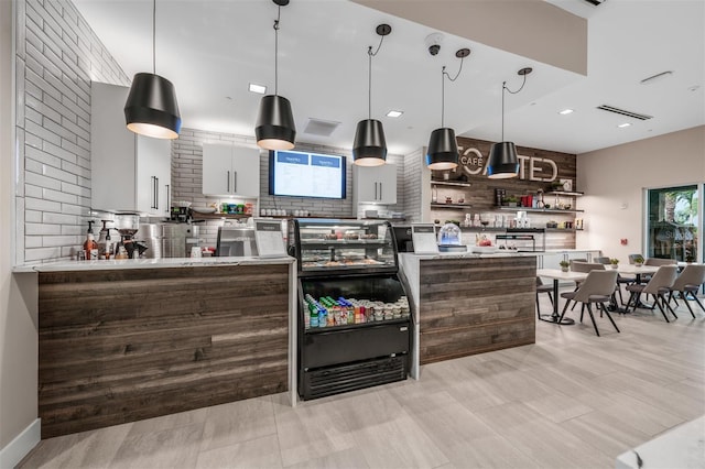 kitchen with white cabinets, decorative light fixtures, light hardwood / wood-style floors, and backsplash